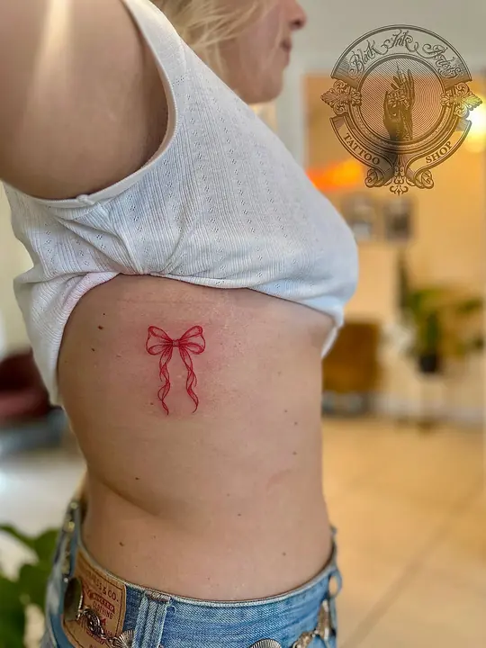 Fine line bow tattoo on ribs