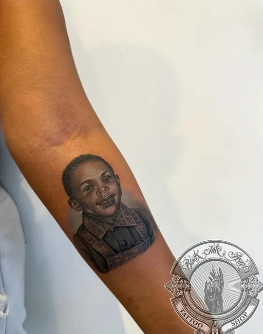 Realism portrait of a young boy, tattooed on the forearm
