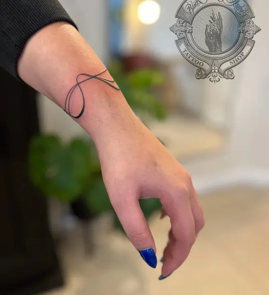 Fine line thread tattoo on wrist